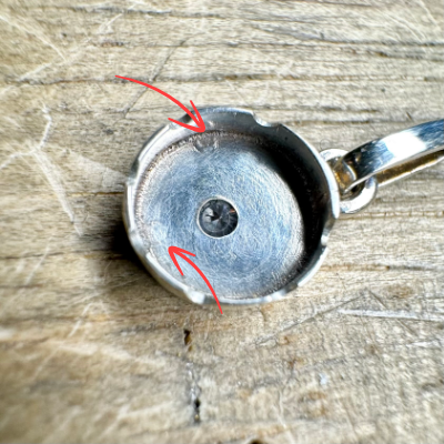 The back side of the silver pendant showing solder etched into the metal